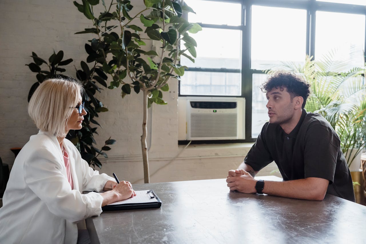 Two professionals engaged in a discussion in a modern office with natural light and plants.